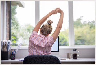 Mulher se alongando na mesa de trabalho